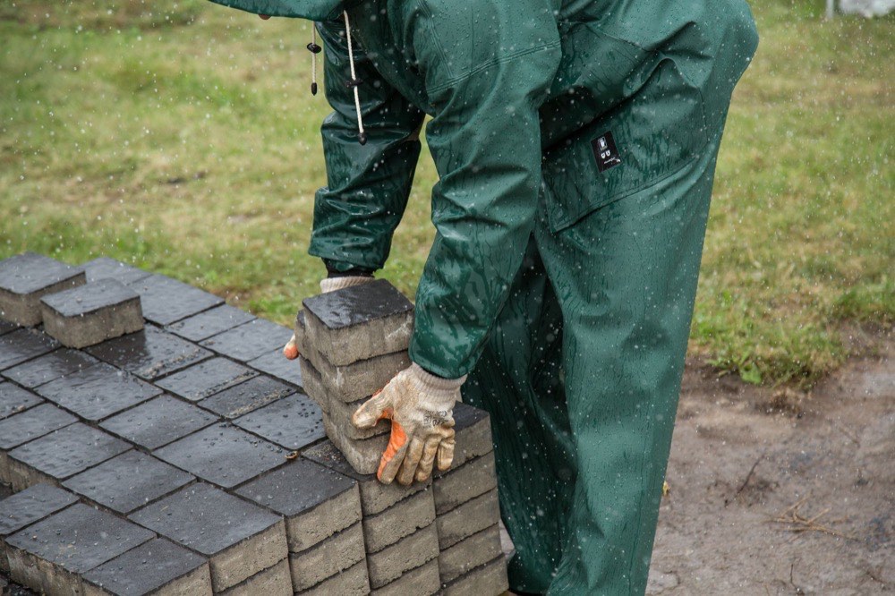 Installer setting concrete pavers by hand on a prepared bedding course