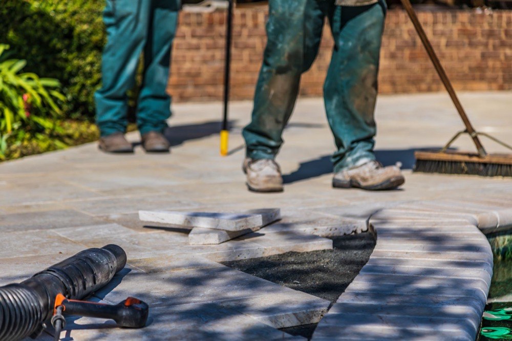 Crew laying paver patio stones over a leveled base